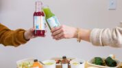 Organic Krush - seasonal cleanse - two hands toasting with Organic Krush Juices above fresh menu options