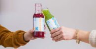 Organic Krush - seasonal cleanse - two hands toasting with Organic Krush Juices above fresh menu options