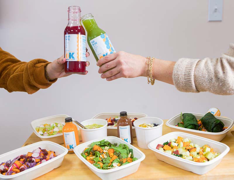 Organic-Krush-seasonal-cleanse-800px Organic Krush - seasonal cleanse - two hands toasting with Organic Krush Juices above fresh menu options